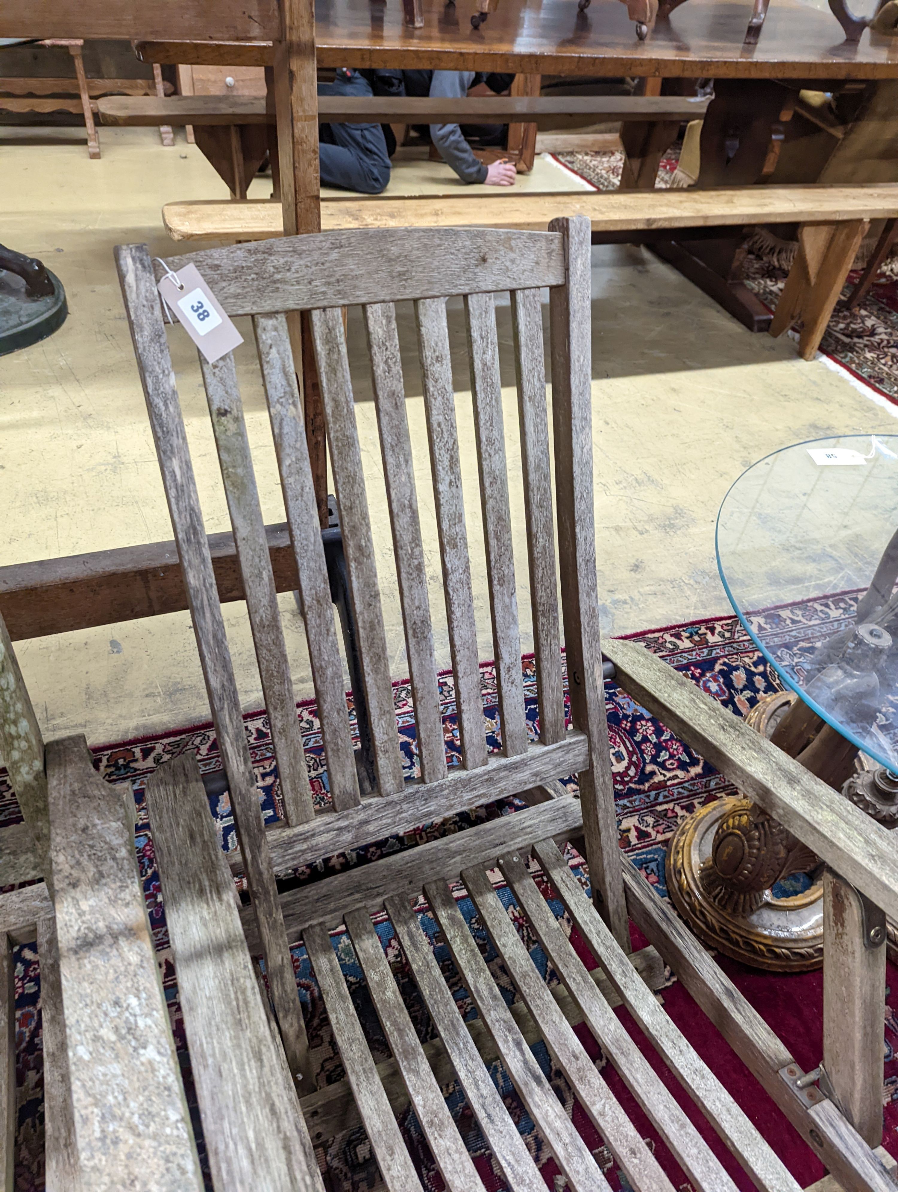 Two weathered teak garden steamer chairs. Heights for both chairs, 102cm and 88cm.